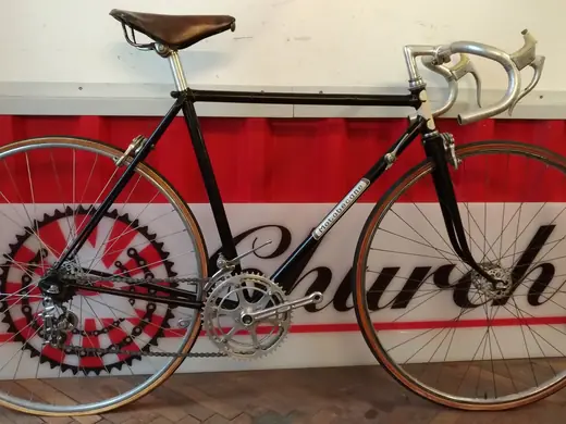 Schwarzes Vintage-Rennrad vor dem Banner der Church of Bikes.